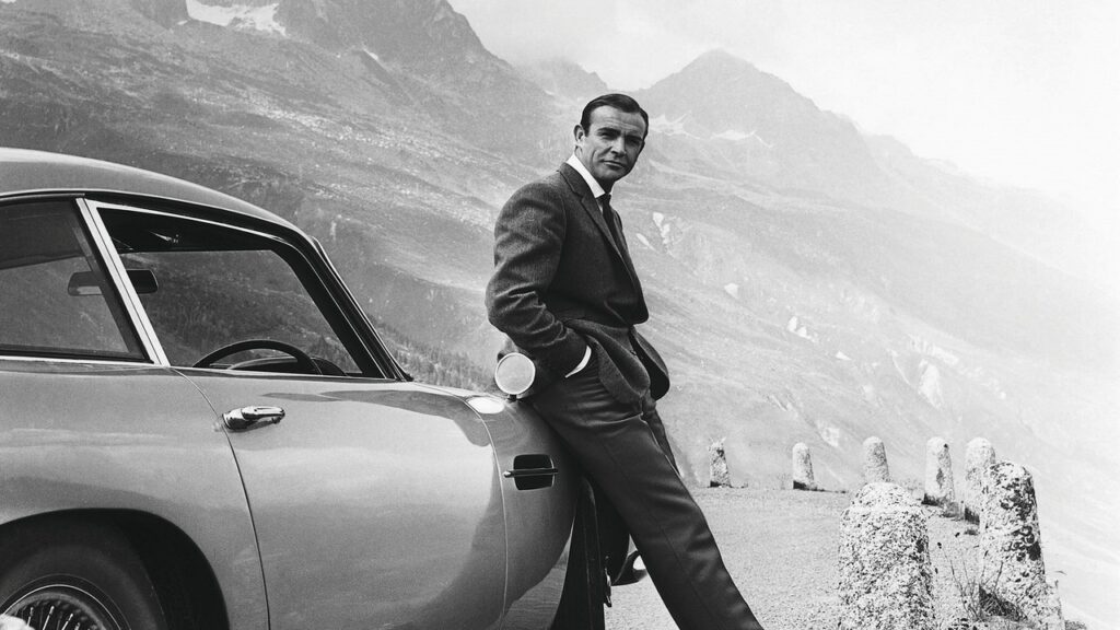 Sean Connery como James Bond apoyado en el Aston Martin