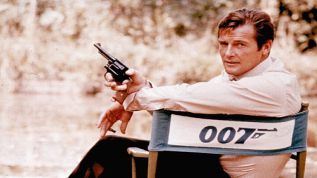 Roger Moore sentado en una silla como agente 007